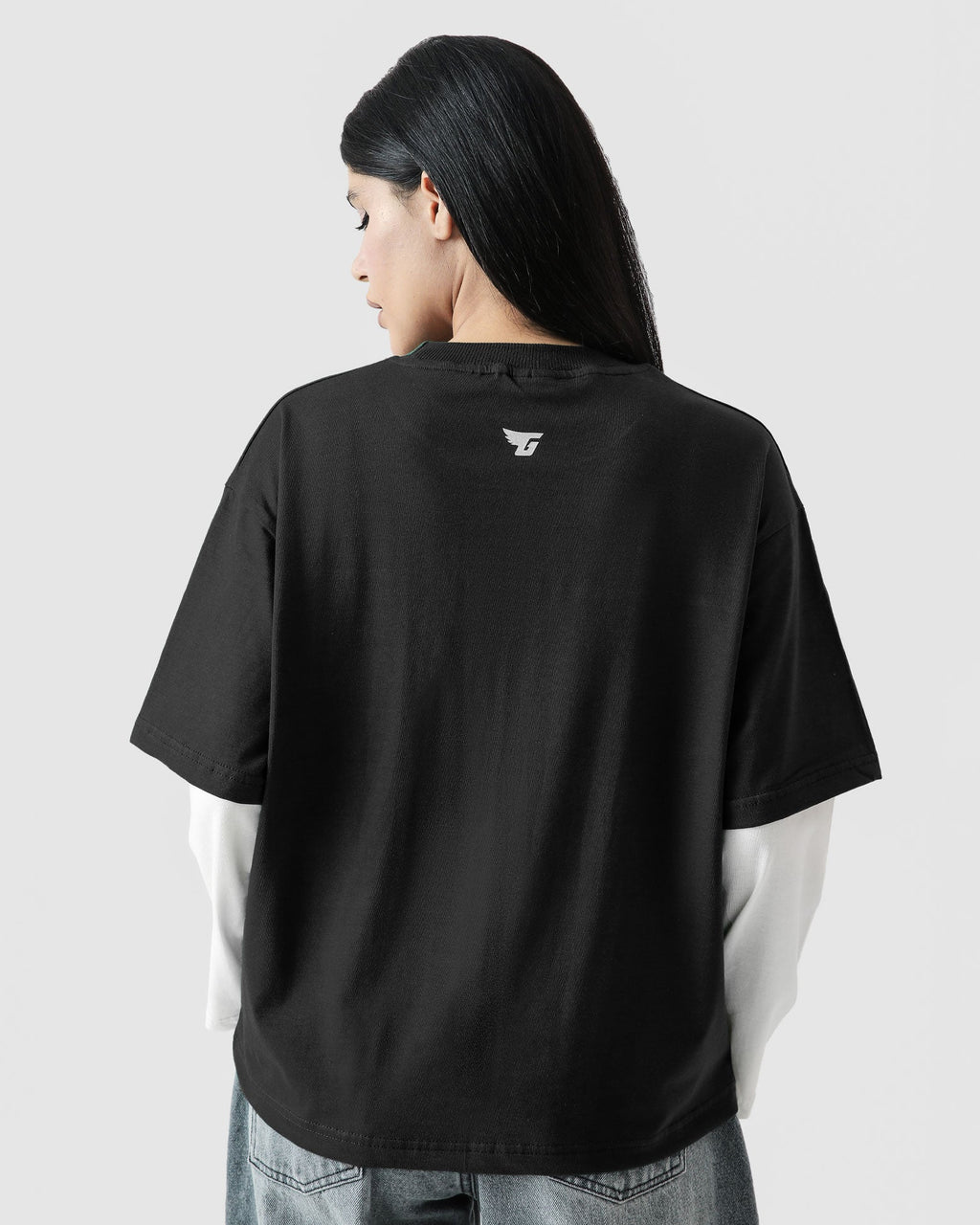 Person wearing a black t-shirt with a logo on the back against a light gray background