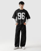 Person wearing a black oversized t-shirt with the number 96 and black pants on a white background