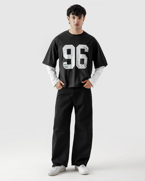 Person wearing a black oversized t-shirt with the number 96 and black pants on a white background