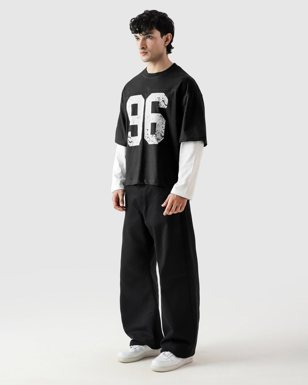 Person wearing a black t-shirt with the number 96 and black pants on a white background