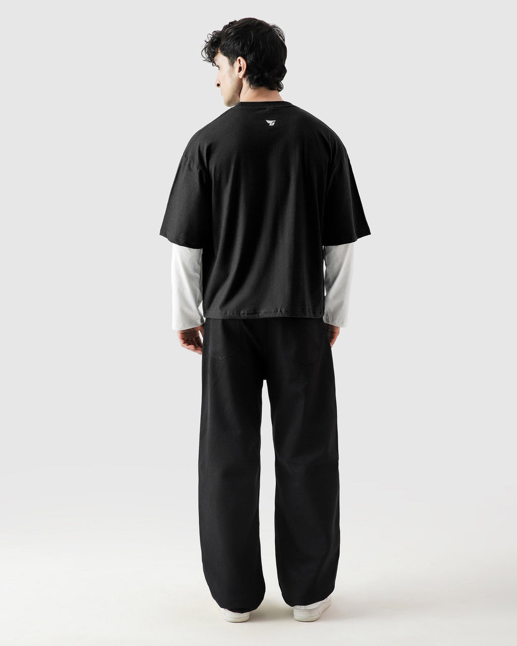 Person wearing a black t-shirt and pants with a white shirt underneath on a white background