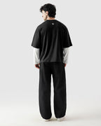 Person wearing a black t-shirt and pants with a white shirt underneath on a white background