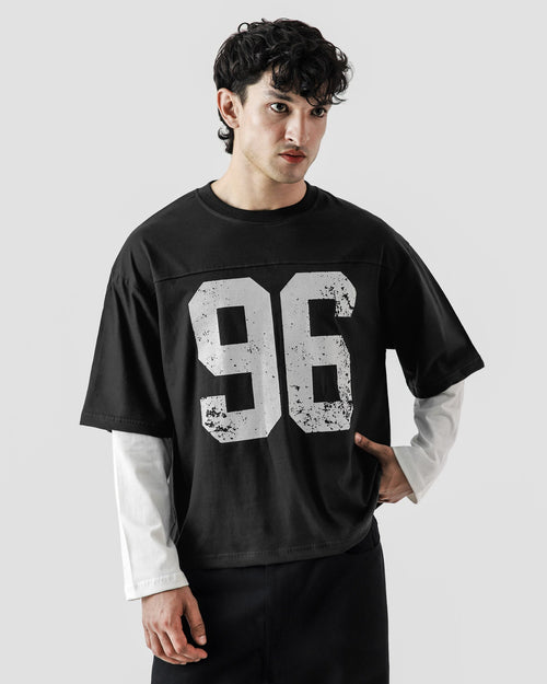 Person wearing a black oversized t-shirt with '96' printed on it against a white background